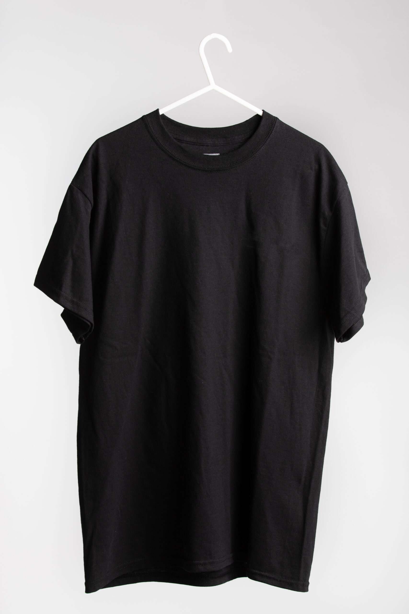 A short sleeve shirt on cloth hanger with white wall in the background